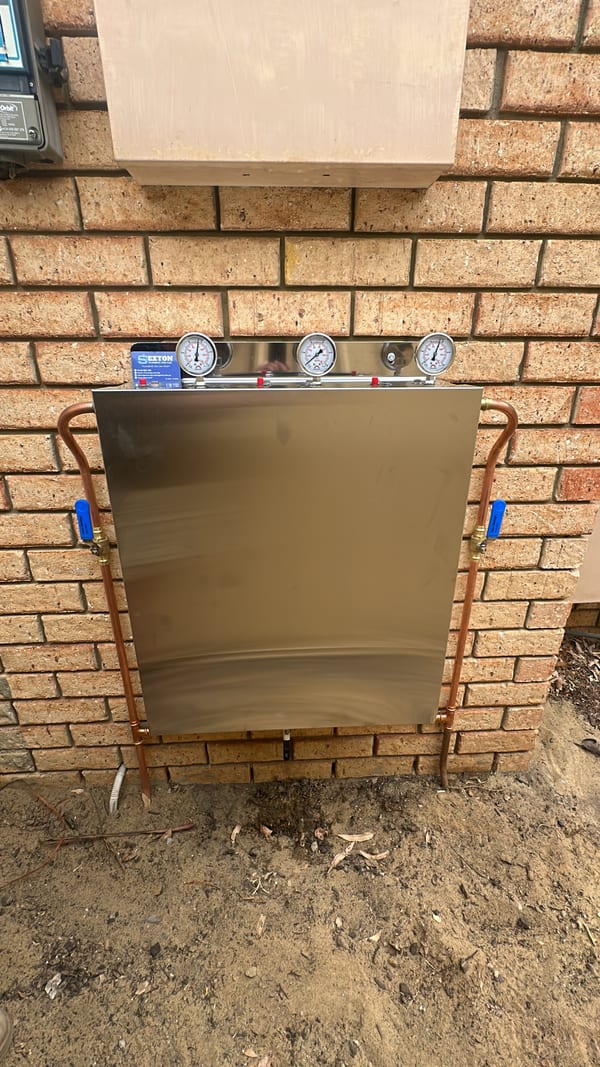 Licensed gas-fitter connecting a stainless gas cooktop in a kitchen benchtop